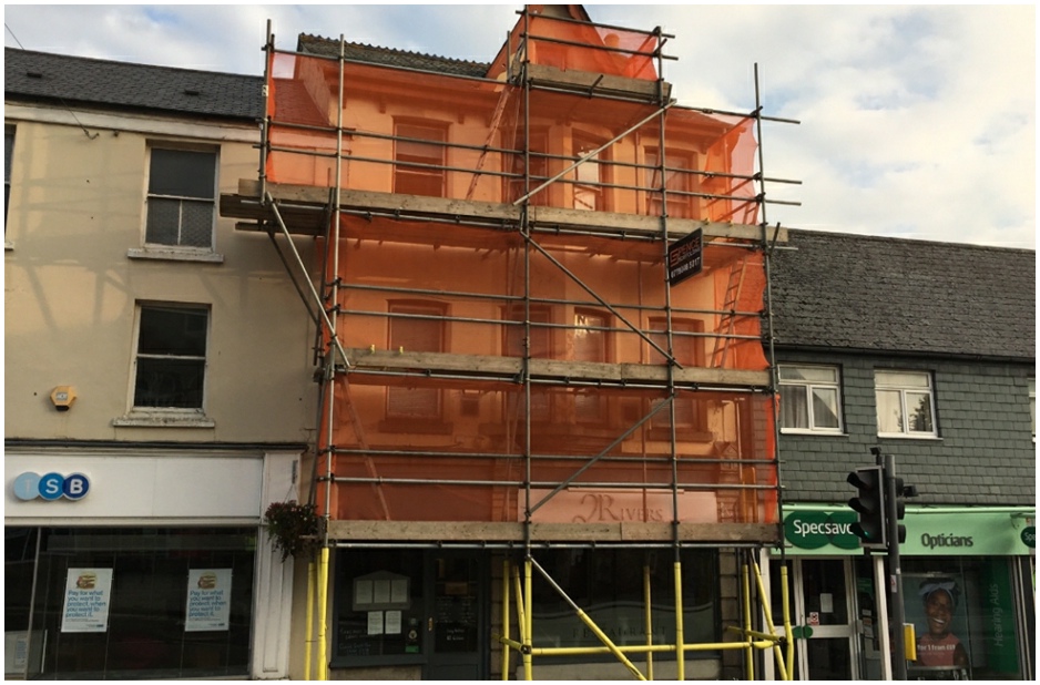 Multi-story scaffolding wrapping a historic Devon high street building