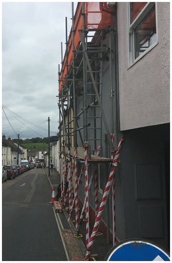 Scaffolding along a Devon street with orange netting